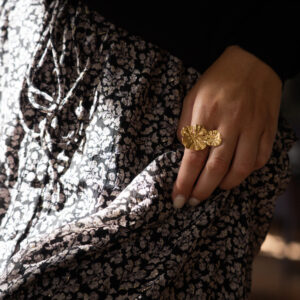 Modèle qui porte un pull noir, une jupe à fleurs et des bijoux June&River