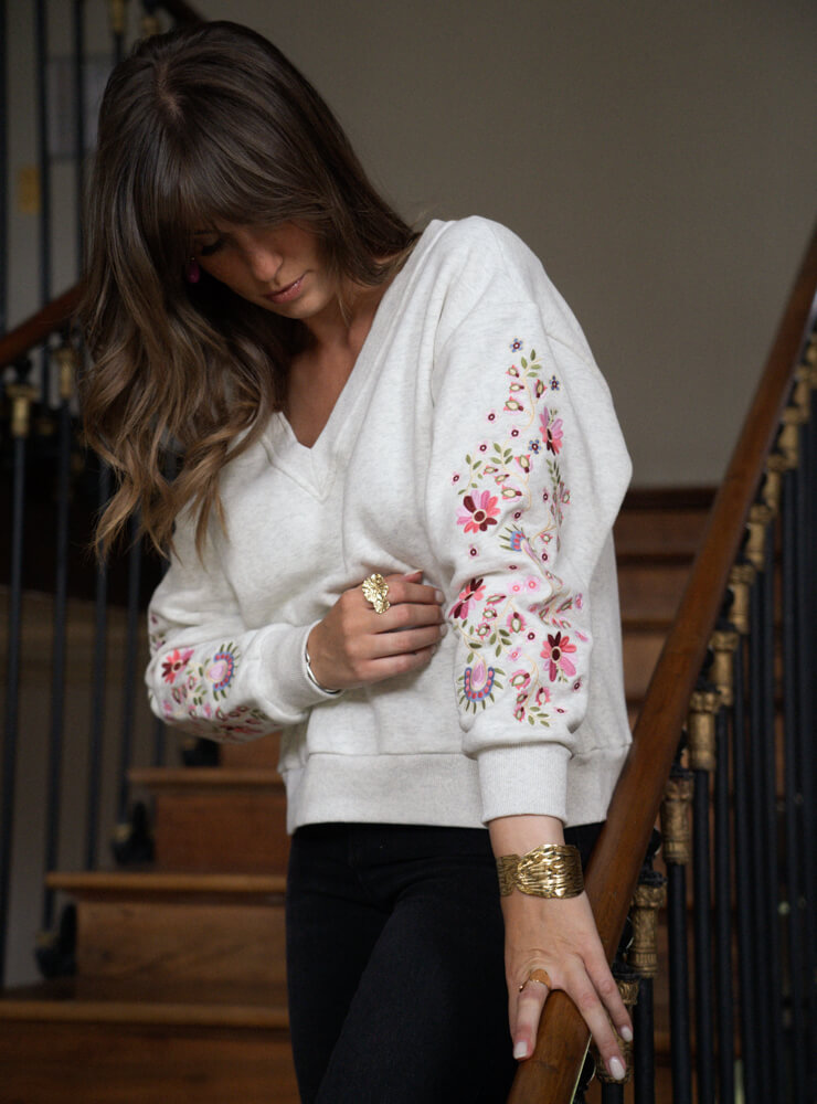 Modèle qui porte un pull à motif, un pantalon noir et des bijoux June&River