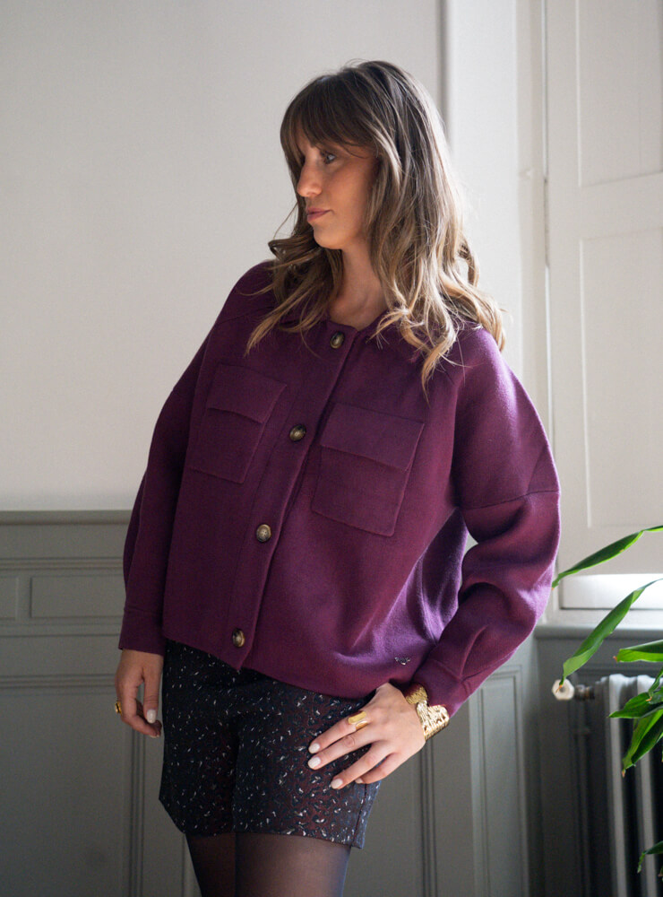 Modèle qui porte une veste violette, un short à motif et des bijoux June&River