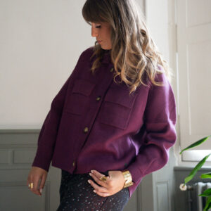 Modèle qui porte une veste violette, un short à motif et des bijoux June&River