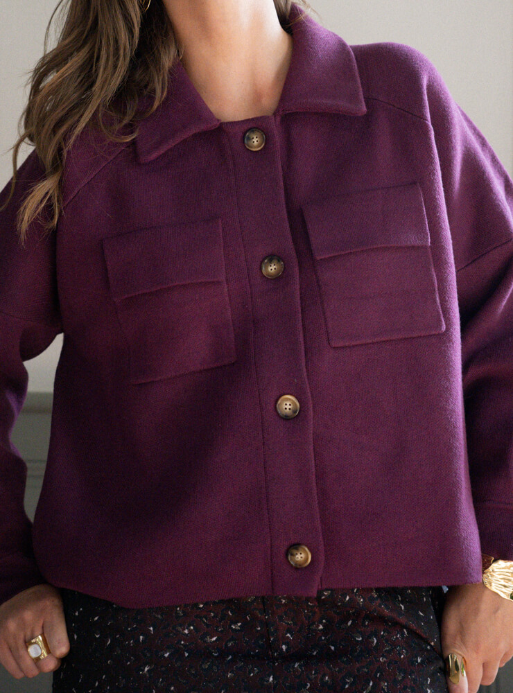 Modèle qui porte une veste violette, un short à motif et des bijoux June&River